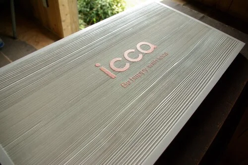 iccaオレンジロゴの白い木製看板